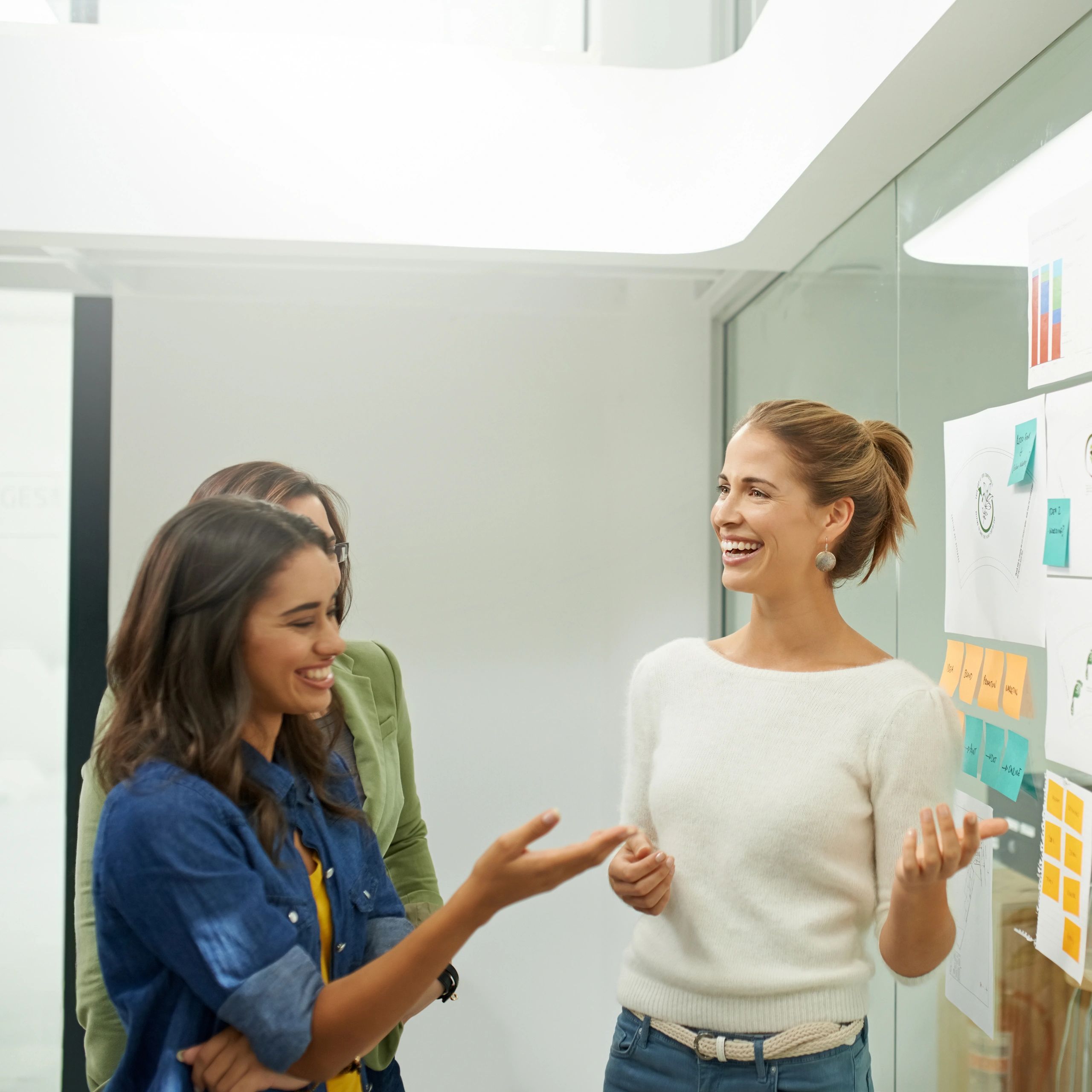Coworkers brainstorming with sticky notes on a glass wall